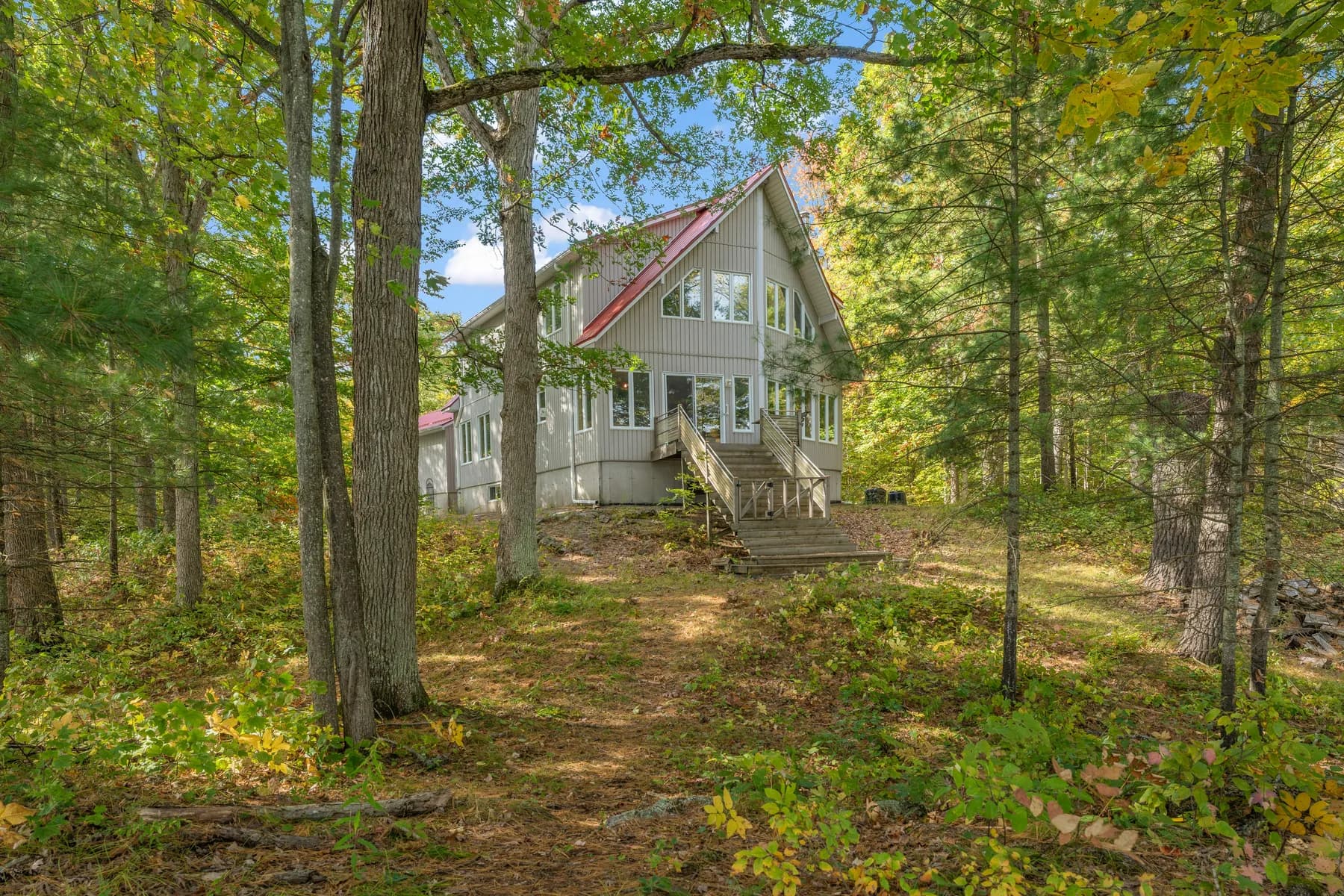 Two-storey home with a red roof set among mature trees
